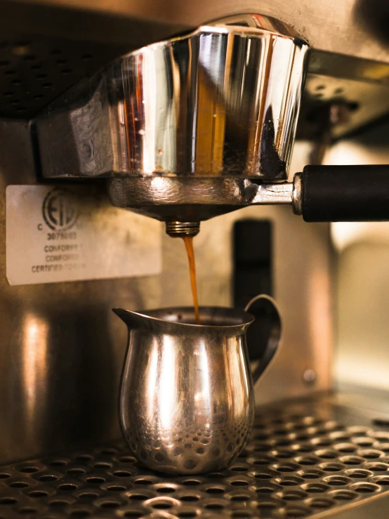 a person's hand making coffee from an espresso