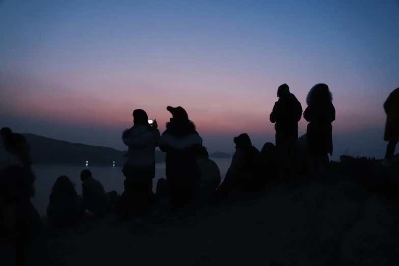 people in the dark near some water and clouds