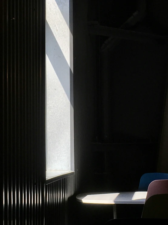 a chair sitting next to a window with light streaming through it