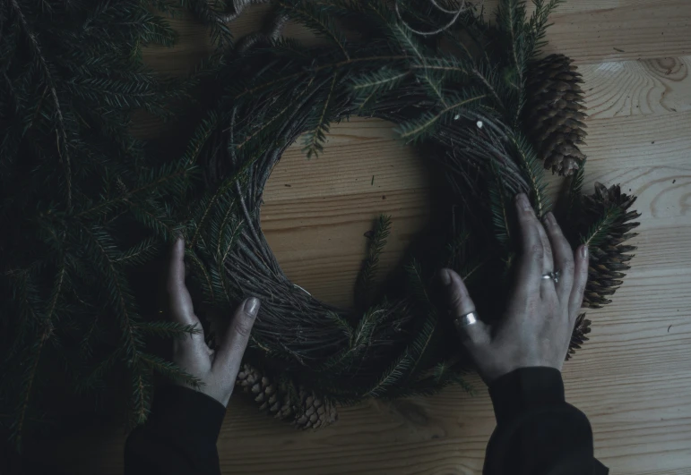 someone is making a wreath using pine cones