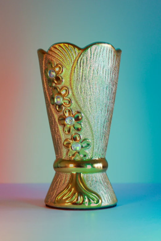 a metal vase sitting on top of a blue and green surface