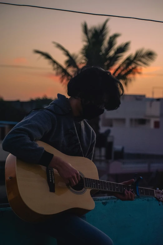 a person playing guitar and singing while sitting outside