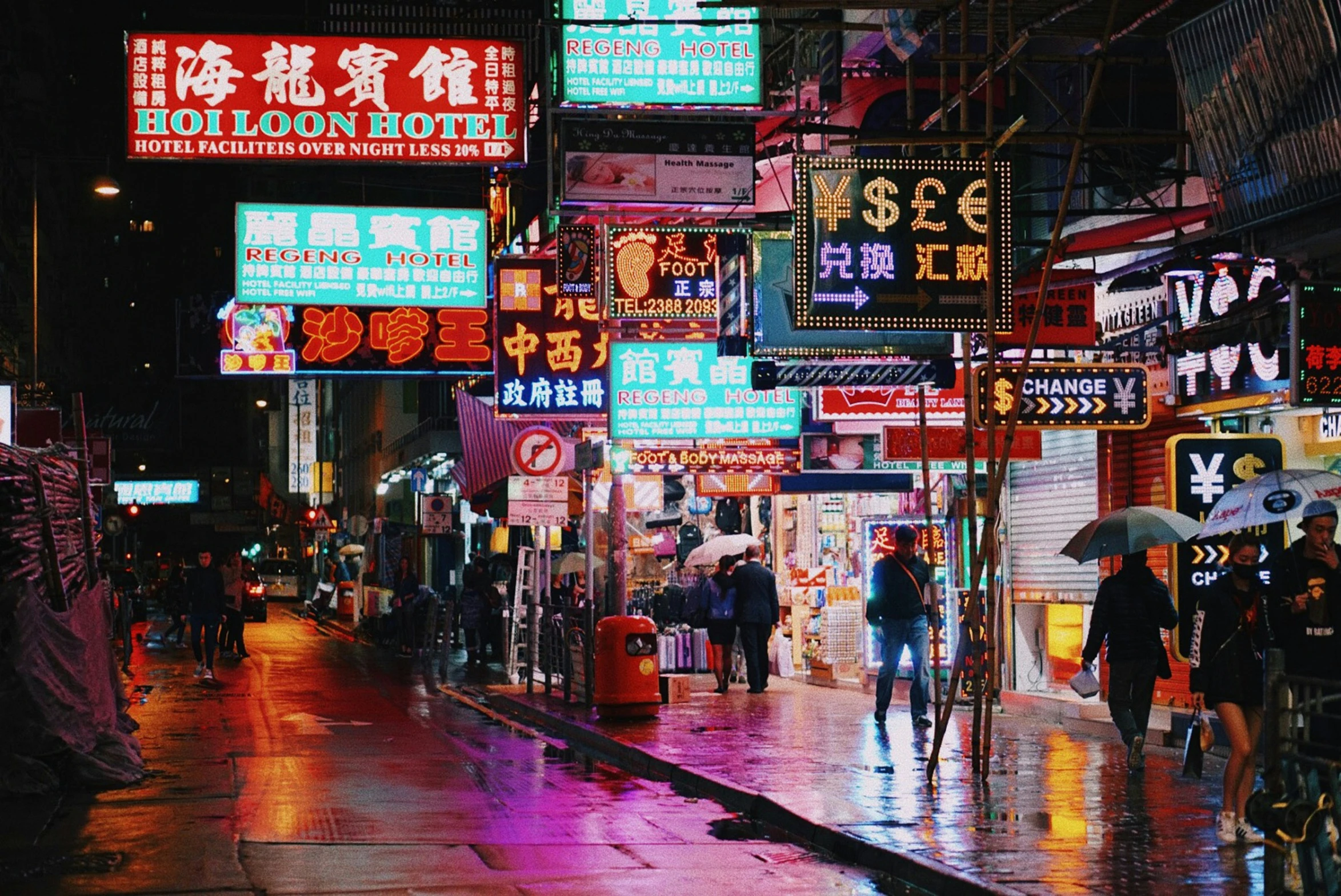 people walking on the sidewalk in the city at night