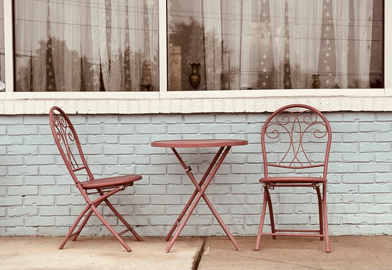 two red chairs and a table are set up on the street