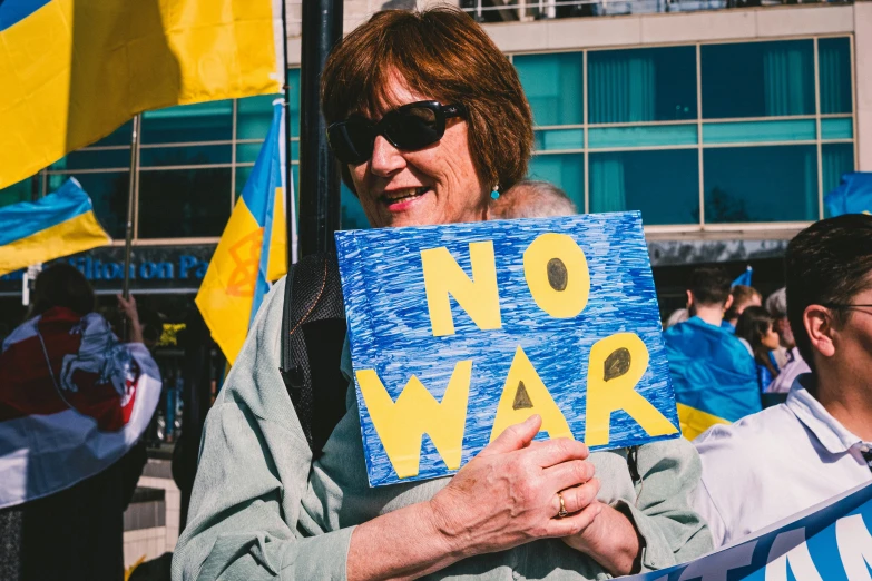 a woman holds up a sign saying no war in the middle of a protest