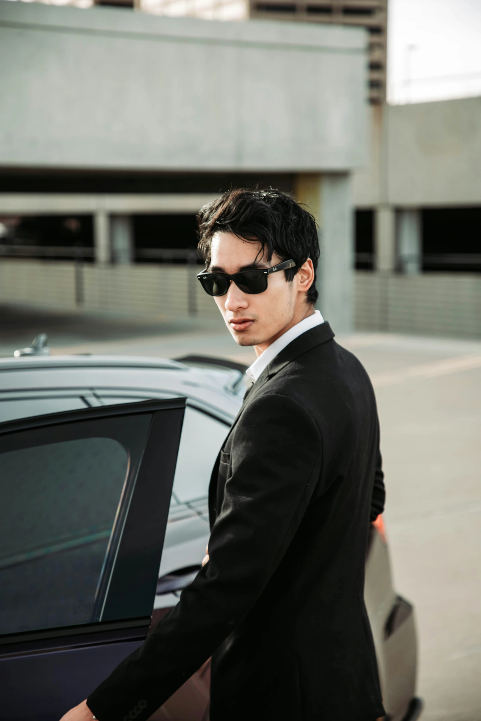 a man in a black suit next to a car