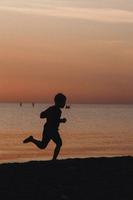 the person is running along the beach with their shadow on the sand