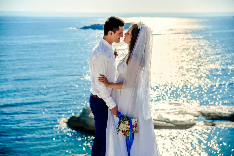 a couple poses for their wedding po by the water