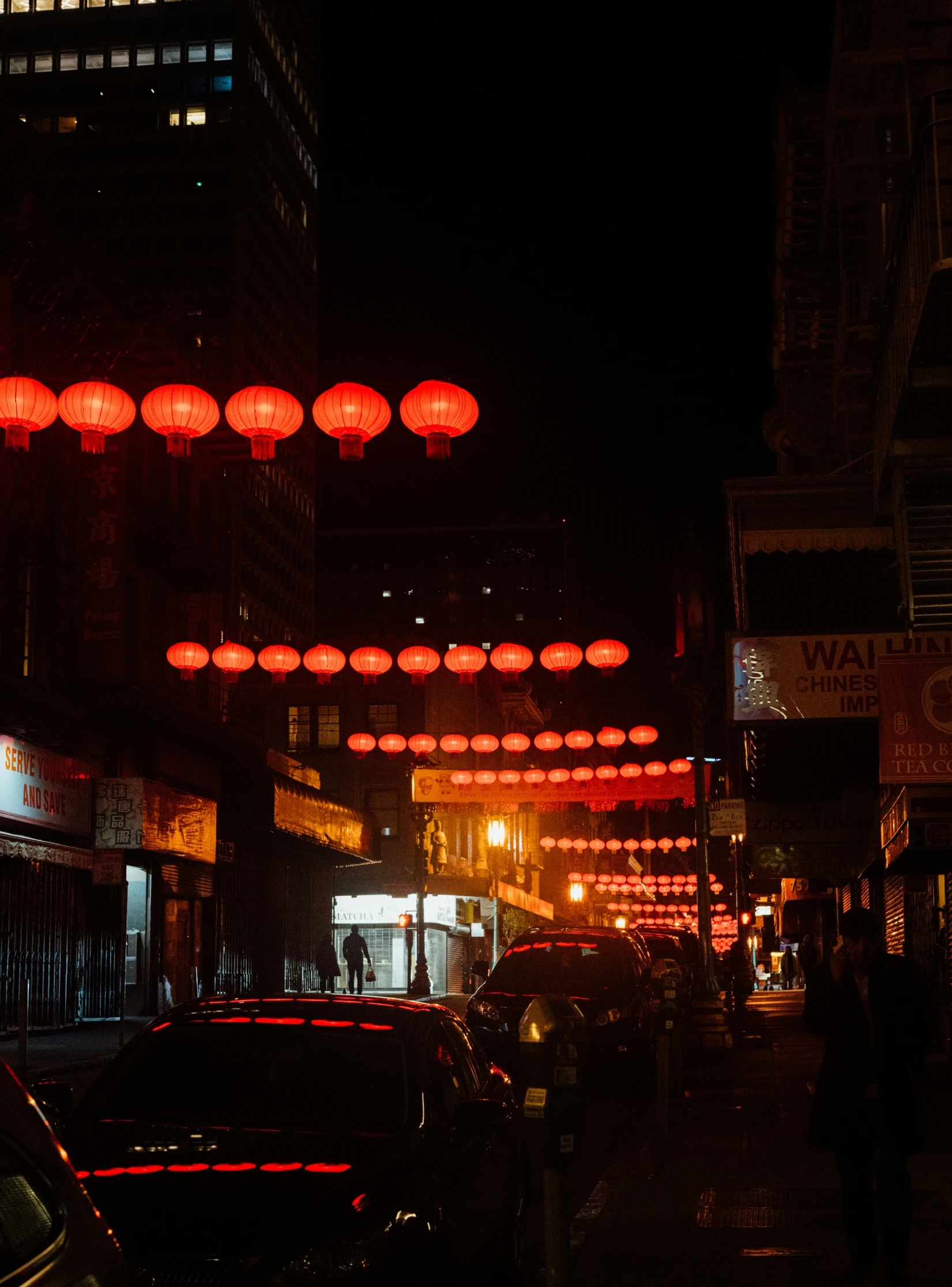 many lamps hanging above the city street in the dark