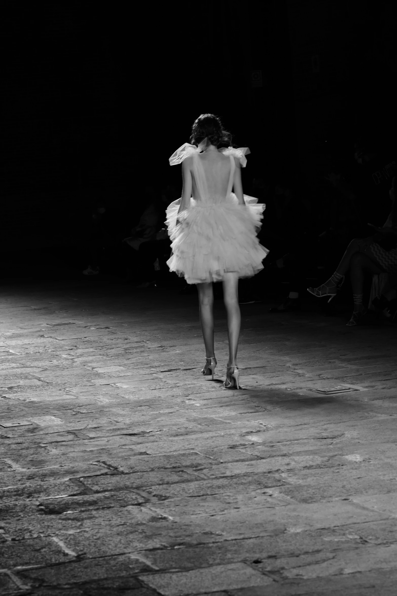 a woman walking down a runway in white clothes