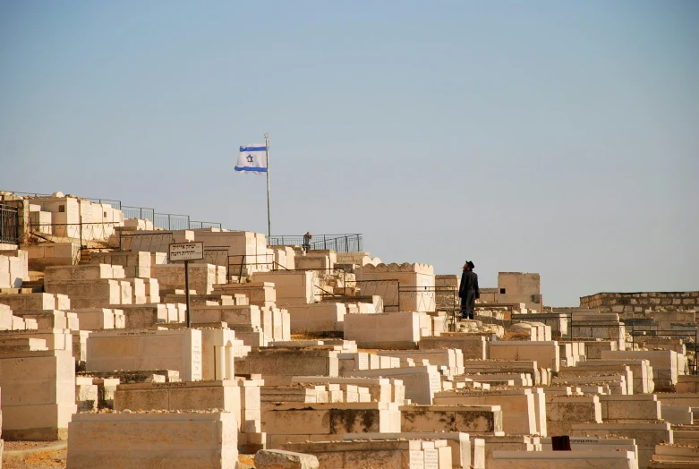 a man is standing on a small hill among rows of white graves