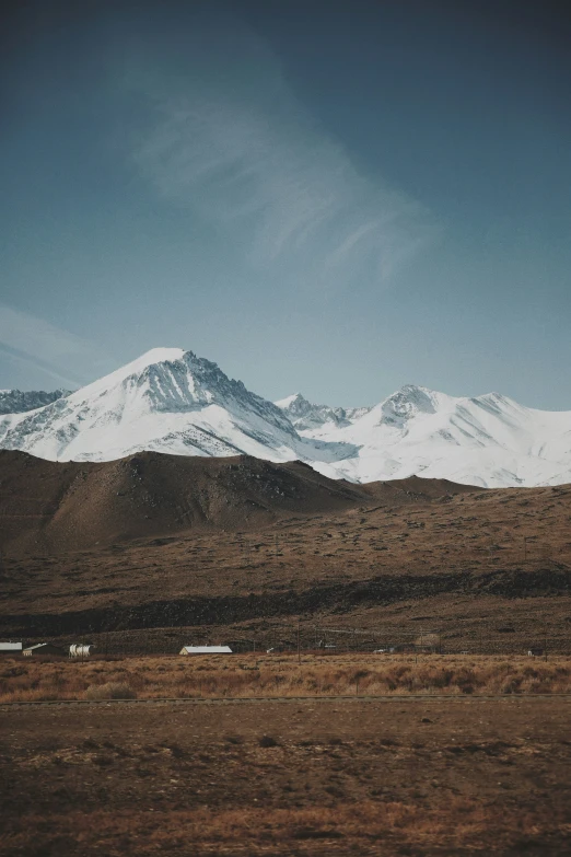 mountains and grassy fields surround a field and some rocks