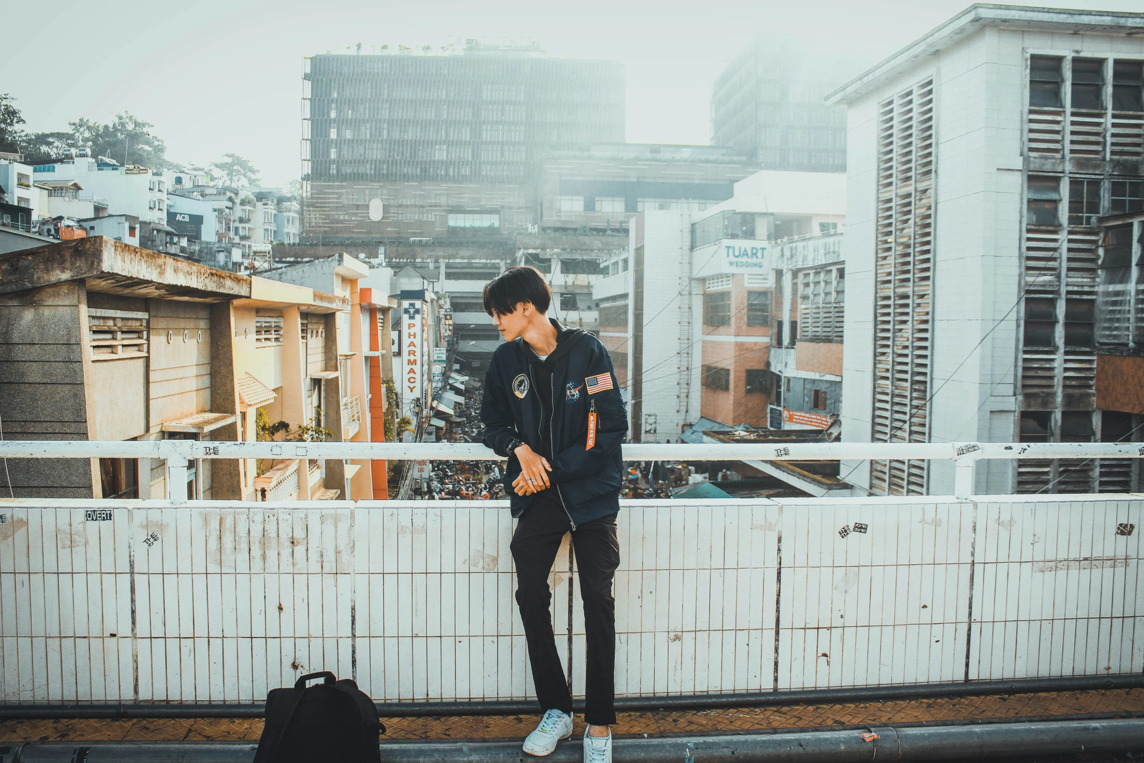 a young man standing on the top of a white bridge