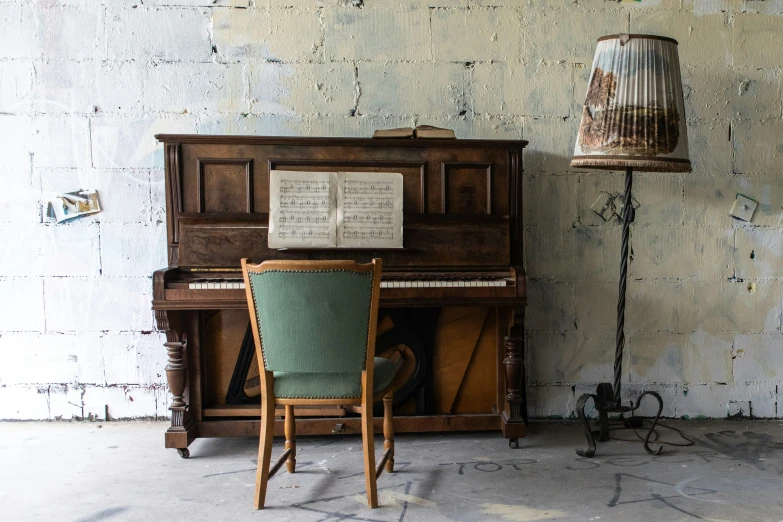 an old piano sits in the corner of a room, with a lamp above it