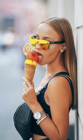 woman eating a ice cream cone and wearing yellow glasses