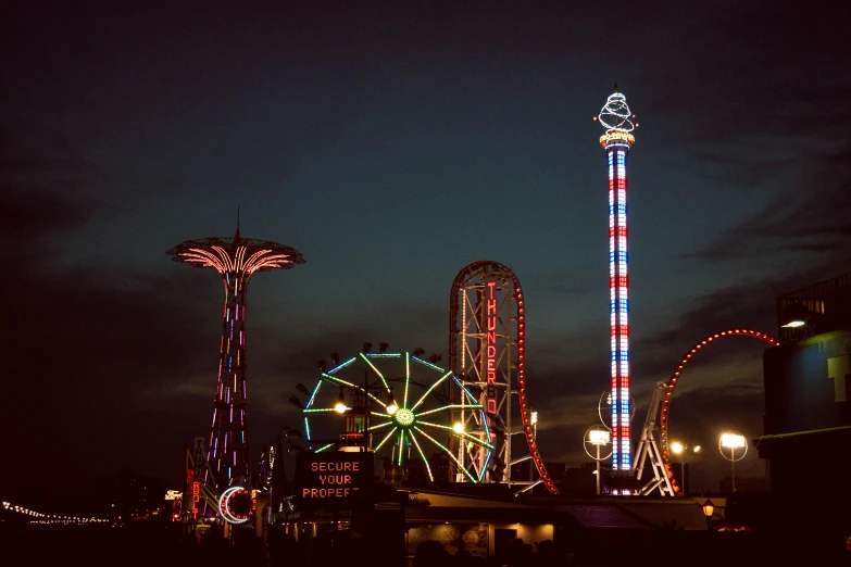 a carnival ride is lit up at night with the ferris wheel visible