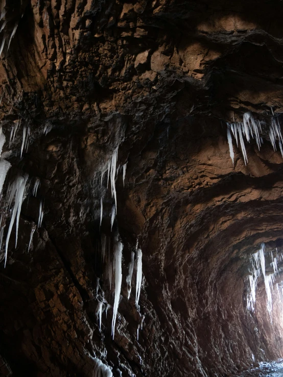 many ice formations in a narrow cave with icicles hanging off the ceiling