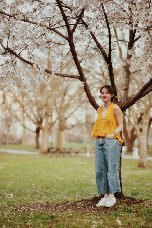 a woman standing under a tree with lots of blossoms on it