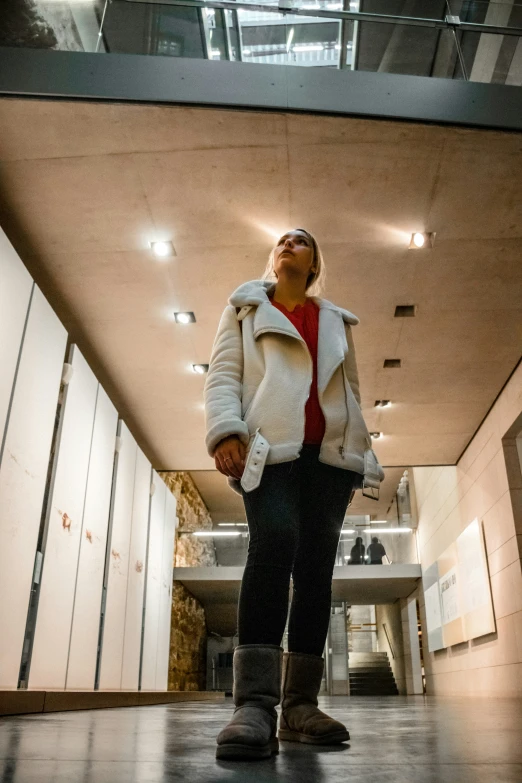 a woman wearing cold weather clothing standing at the entrance to an elevator