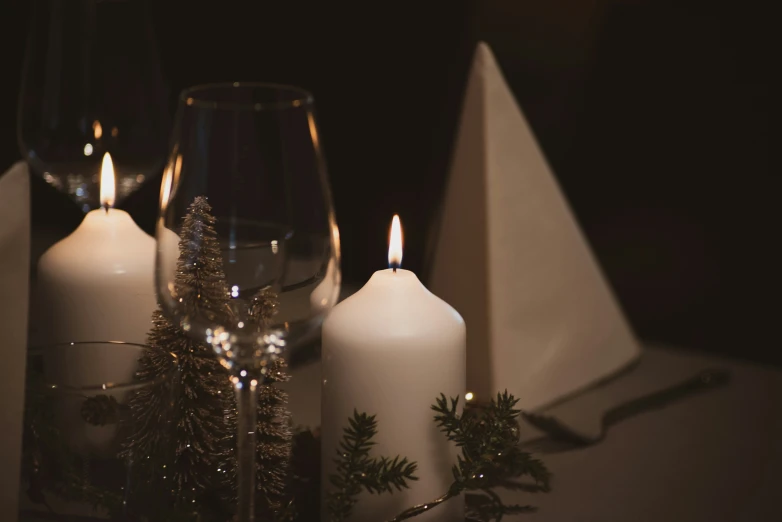 a candle on a table with evergreen needles in front