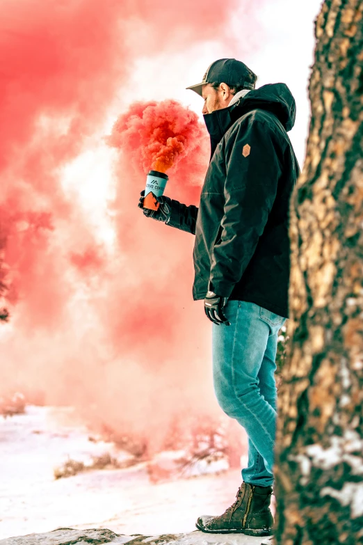 a man holding a red object near a tree