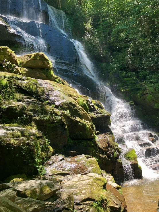 a man swimming in the water in front of a waterfall