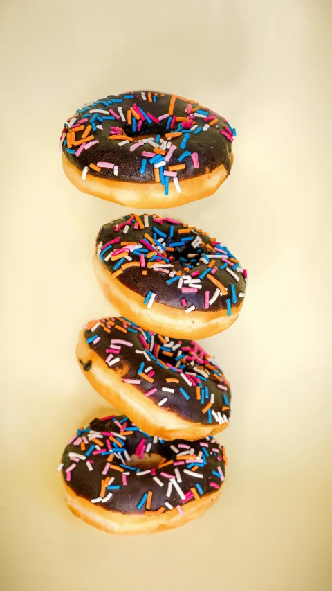 four donuts with various colors of sprinkles in a row