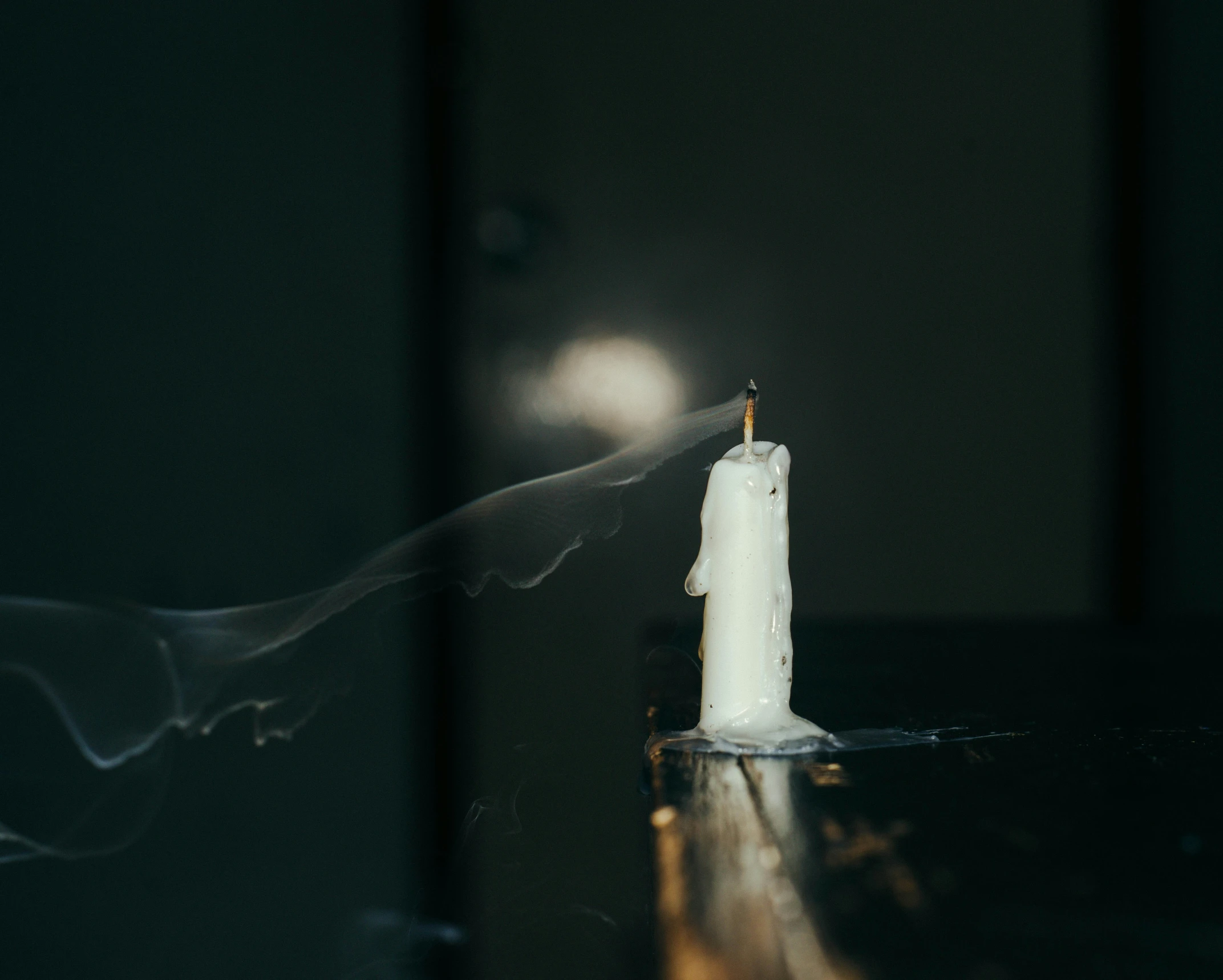 white candle being lit in a darkened room