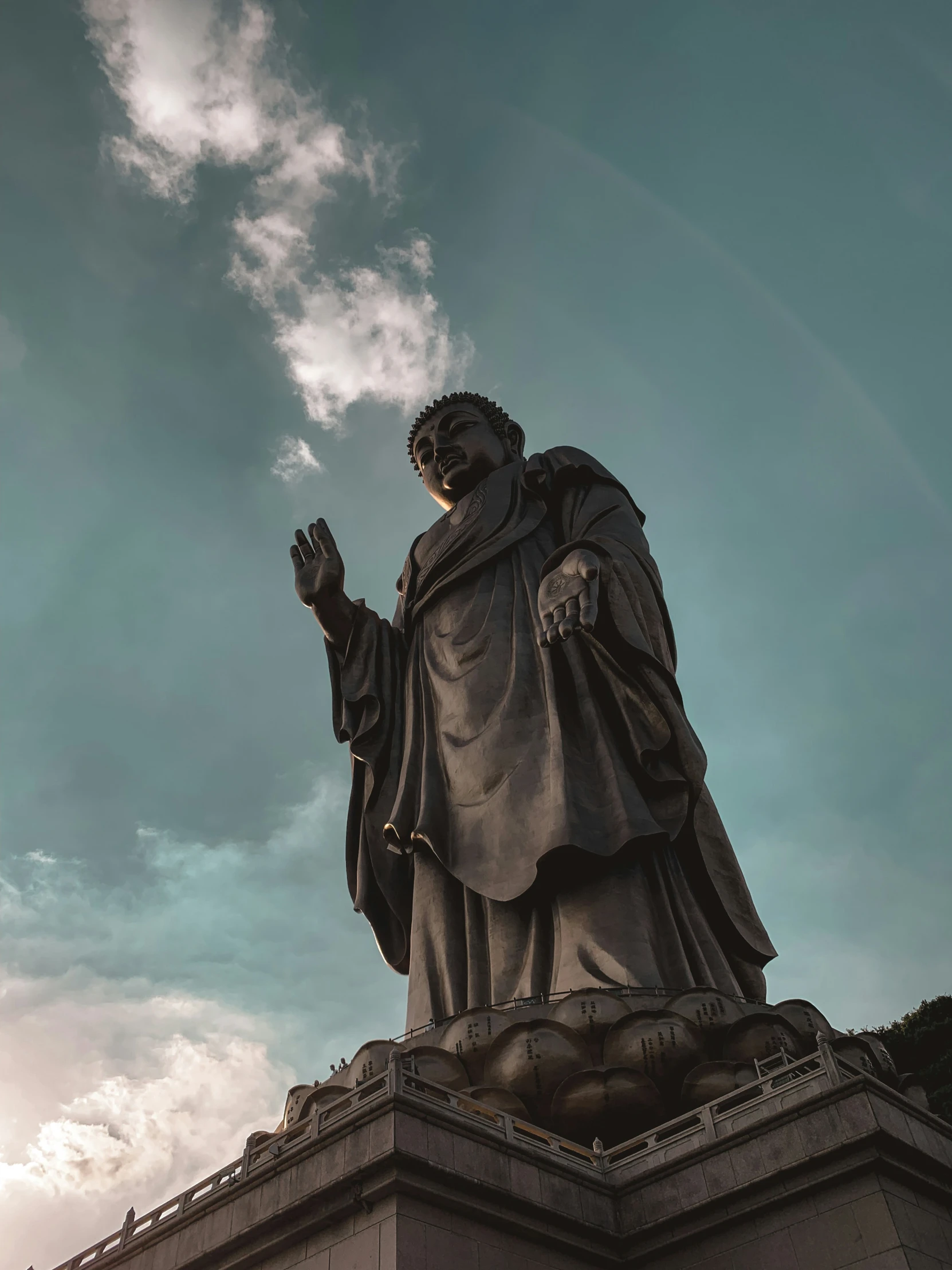 a statue of saint benedict in front of a blue cloudy sky