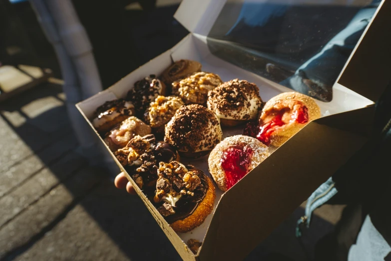 person holding box of different types of donuts