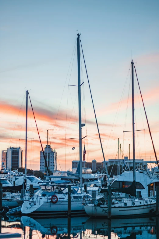 sailboats are moored at a harbor at sunset