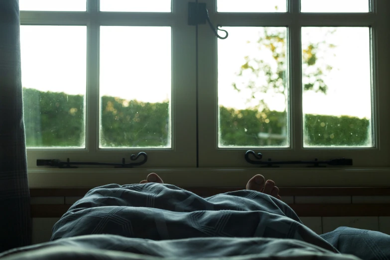 a person is lying down with their feet near the window