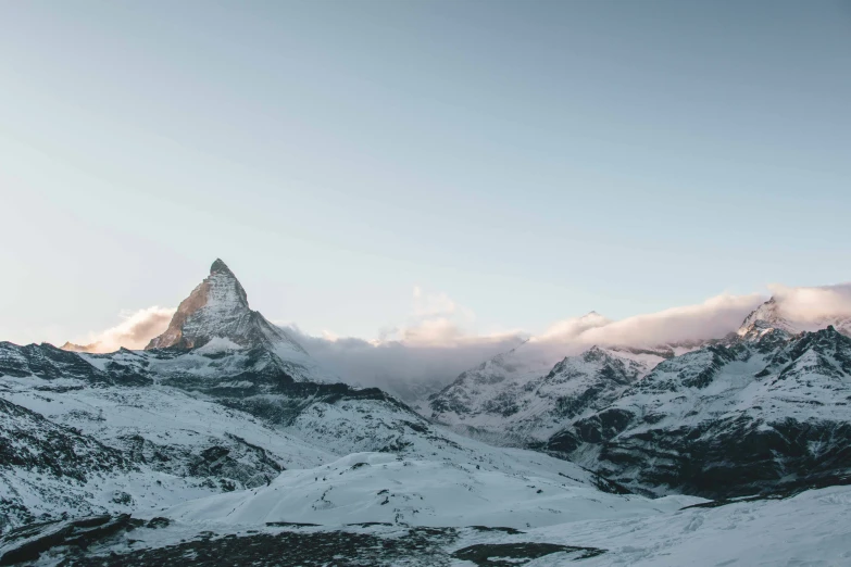 two mountain peaks standing in front of some clouds