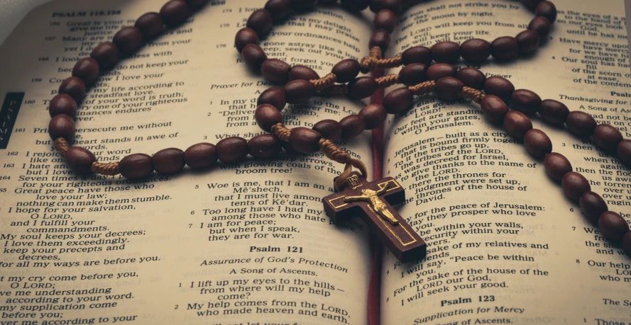 an open bible with a rosary and a cross hanging from it