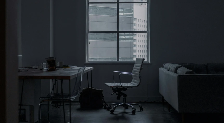 an empty living room with a chair and desk in front of the window