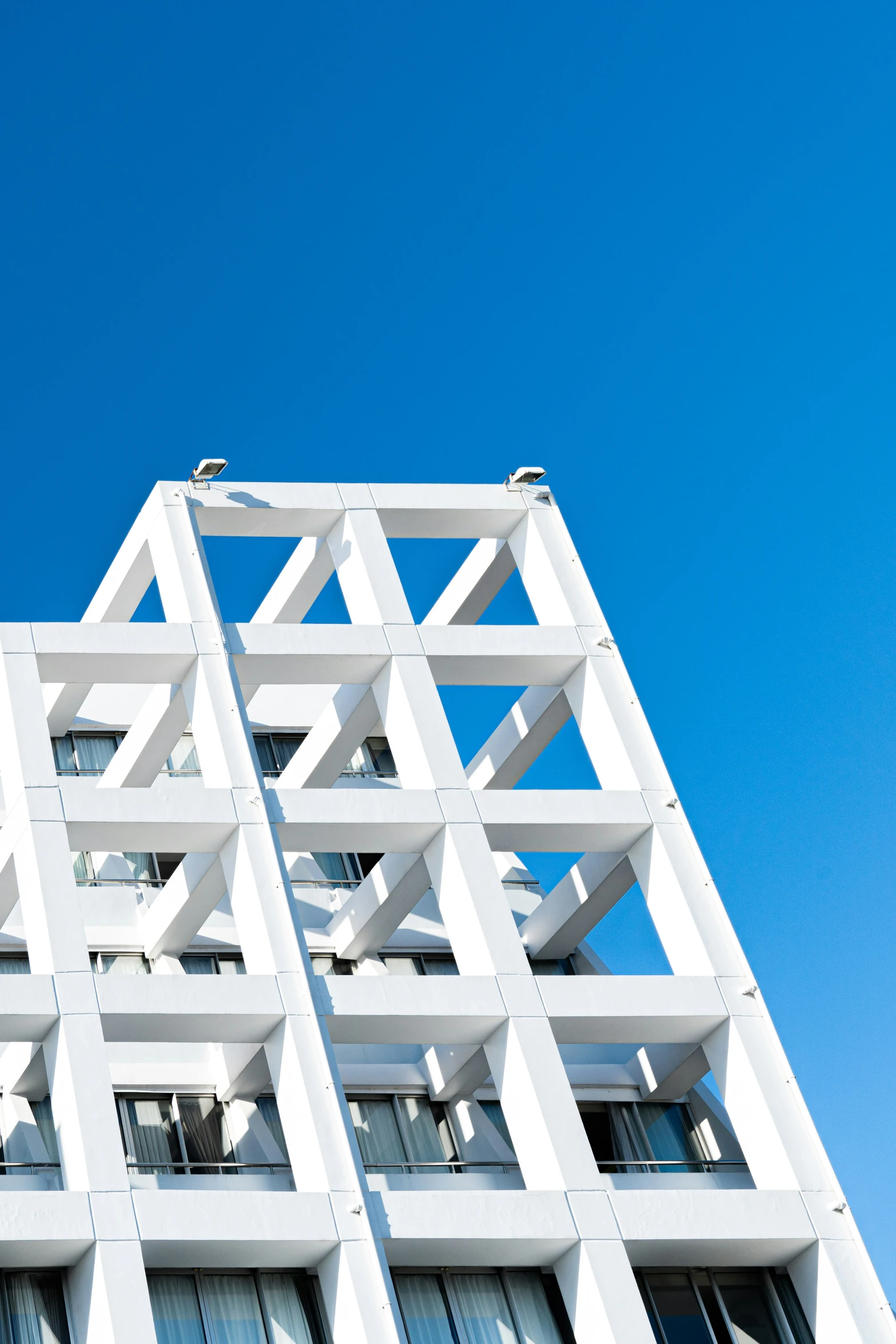 a tall white building with balconies against the blue sky