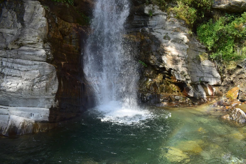 a very large waterfall with green vegetation growing on top