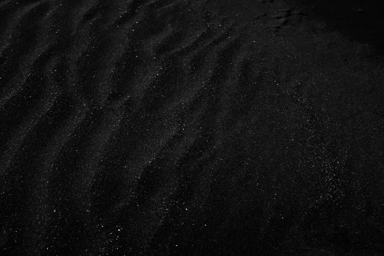 a black sand dune with lots of tiny spots on it