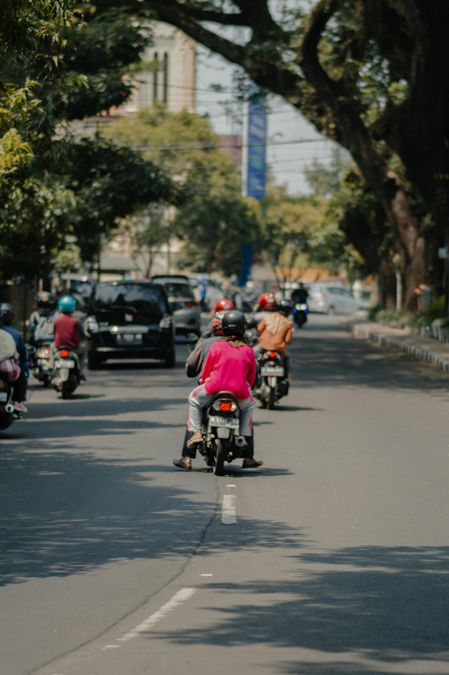 several people on motor bikes going down the street