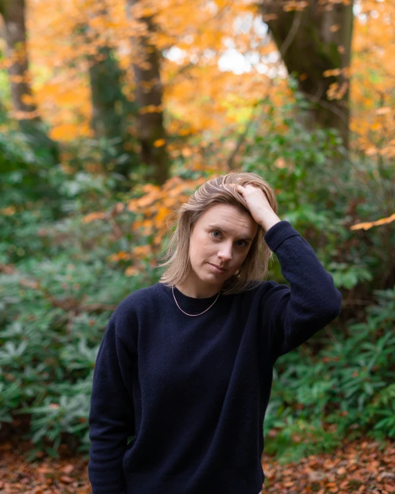 a woman holding her head in front of a forest