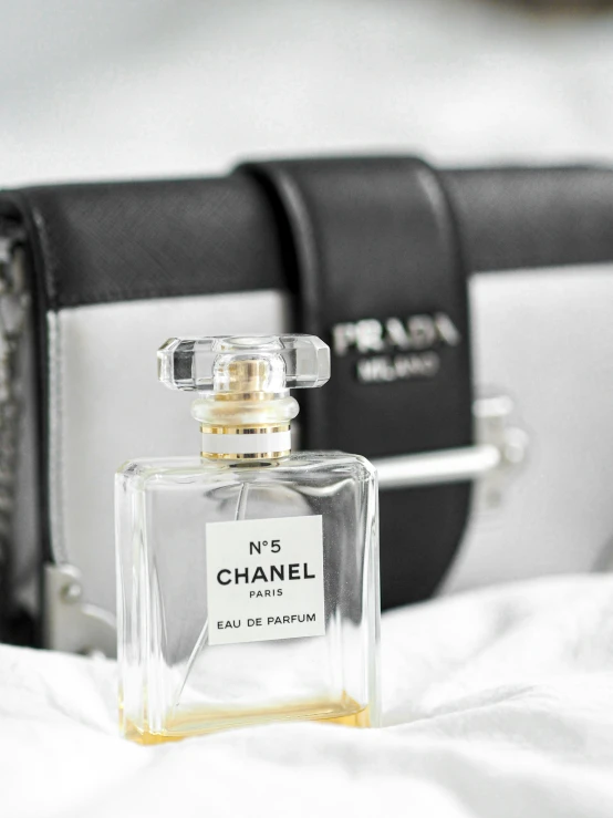 a chanel bottle laying on a bed next to a camera