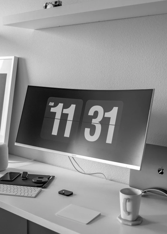 a computer desk has two screens displaying the date 31st november and a cup with a tea mug