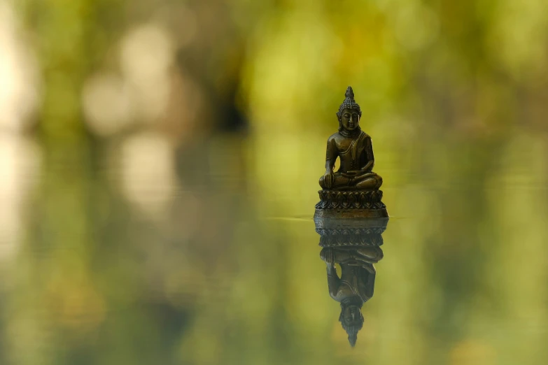 a buddha statue sitting on top of a lake