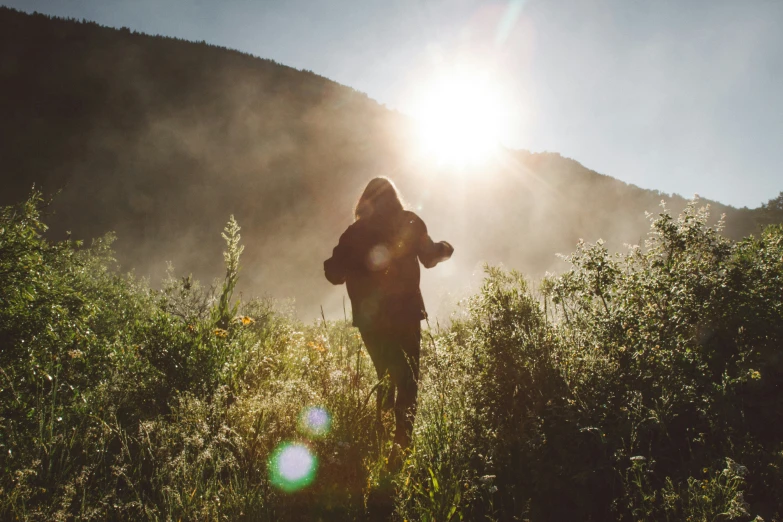 woman standing with hoodie up looking out over grassy field