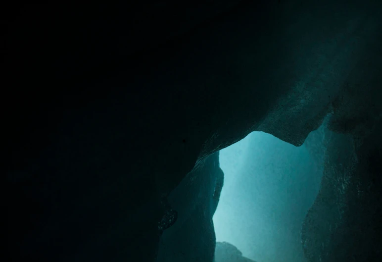 a very dark cave with a bright light coming through