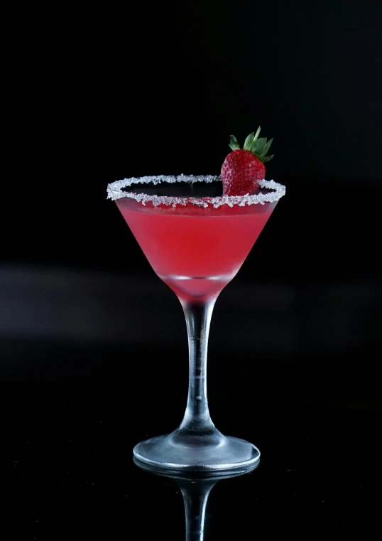 a red cocktail with a strawberry on the rim