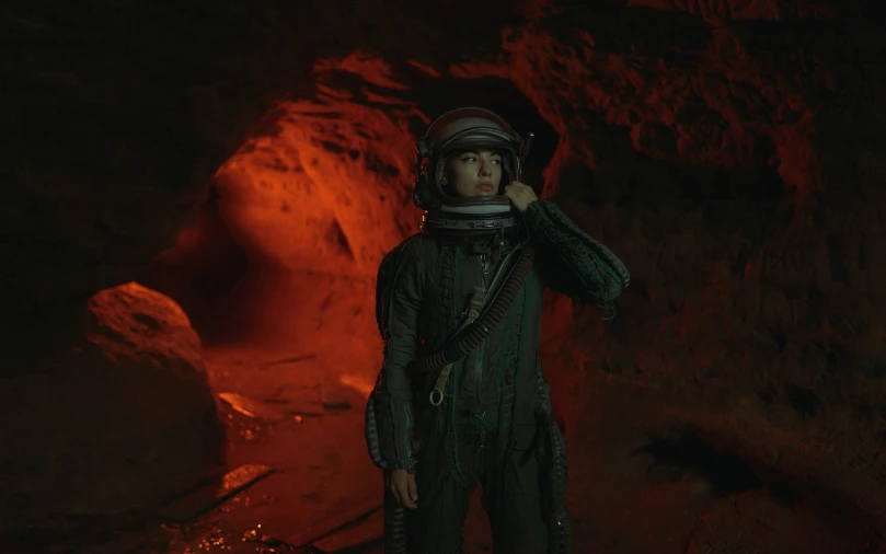 a man standing in front of a dark cave with lava