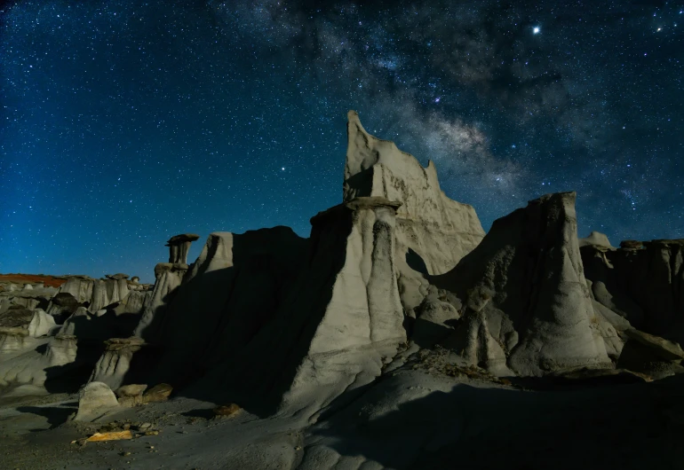 a dark rocky hill covered in rock under stars