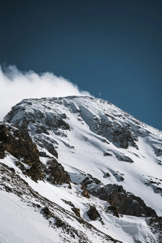 a very tall snow covered mountain with a bunch of clouds