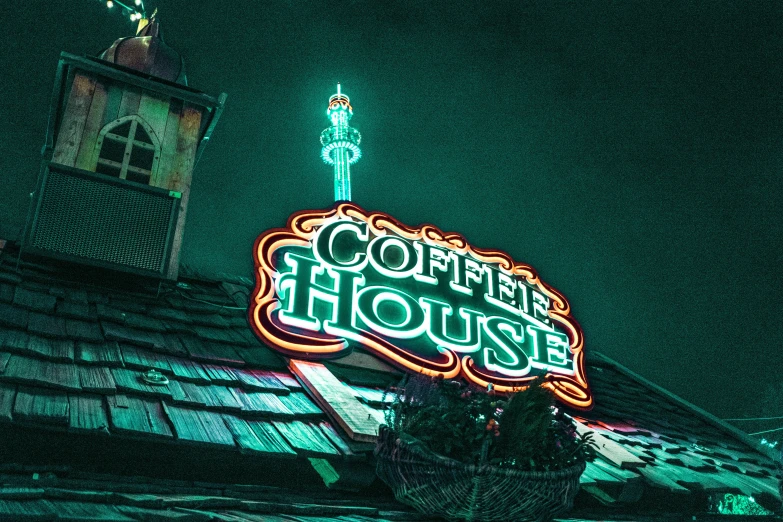 a lit sign on top of a building with the words coffee house